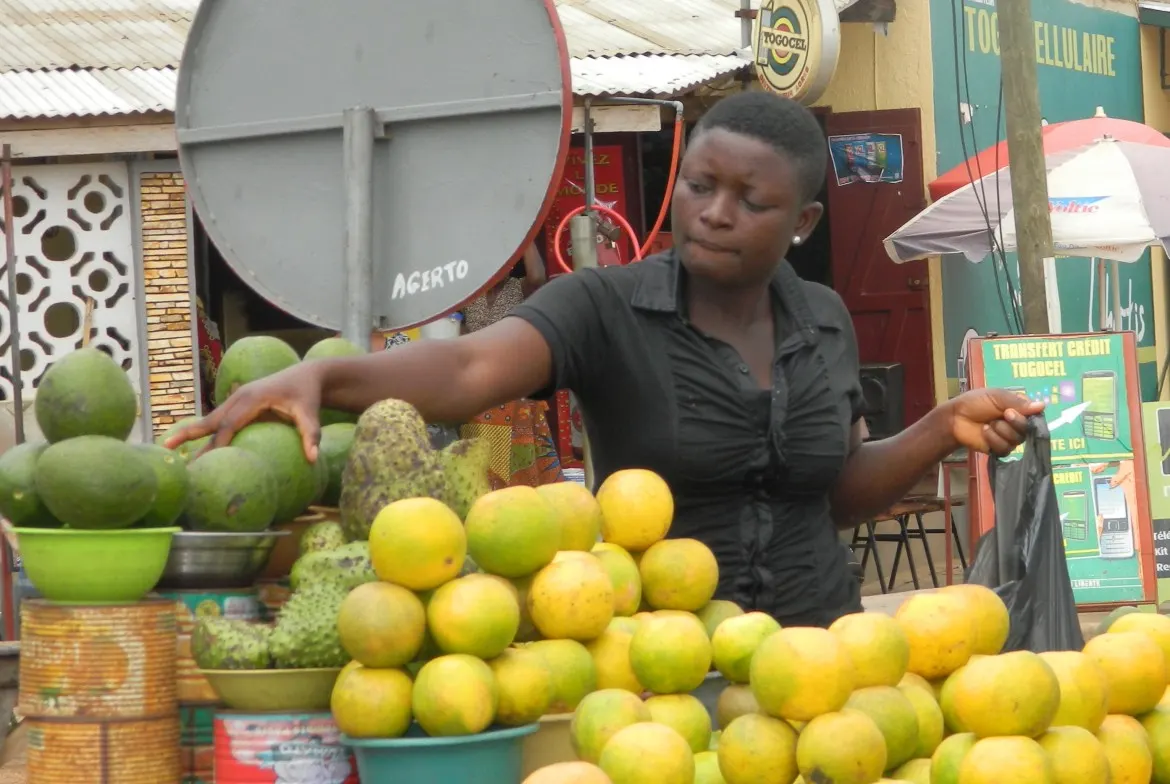 Eine Verkäuferin mit Ananas und Zitrusfrüchten auf einem Markt